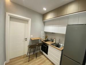 cocina con armarios blancos, fregadero y nevera en Bliss Apartment - Luxury and Cosy, en Berat
