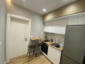 cocina con armarios blancos, fregadero y nevera en Bliss Apartment - Luxury and Cosy, en Berat