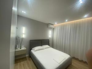 Un dormitorio con una cama blanca y una cortina blanca. en Bliss Apartment - Luxury and Cosy, en Berat