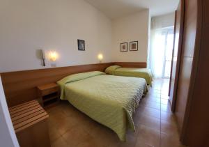 a bedroom with two beds and a window at Hotel Brunella in Rimini