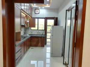 a kitchen with a white refrigerator and wooden cabinets at Maskan in Islamabad