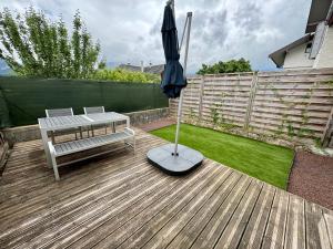 a patio with a table and an umbrella and a bench at Studio avec jardin proche lac in Saint-Jorioz