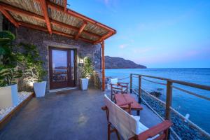 a house on the beach with chairs and the ocean at Petra Elounda Suites - Adults Only in Elounda