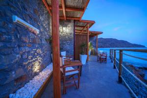 a restaurant with a stone wall and tables and chairs at Petra Elounda Suites - Adults Only in Elounda