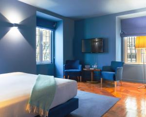 a bedroom with blue walls and a bed and chairs at Villa Cascais Boutique Hotel in Cascais