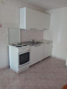 a white kitchen with a stove and a sink at Apartments More in Skrivena Luka
