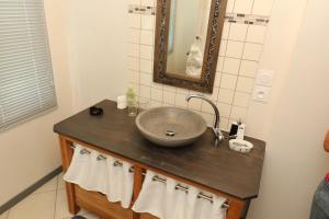 a bathroom with a sink and a mirror and towels at Ndila Cottage avec piscine exclusive in Fatouville-Grestain