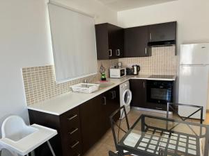 cocina con armarios negros y nevera blanca en Cosy apartment at Mythical Sands resort, en Paralimni