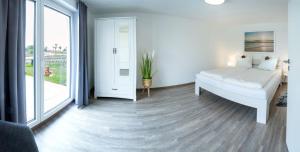 Un dormitorio blanco con una cama y un balcón. en Wasserblick Loddin Comfort 6, en Loddin