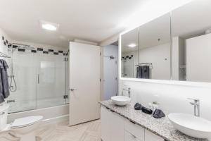 a white bathroom with two sinks and a shower at DT Delight Downtown Living Two-Bedroom Endless Access in Cleveland