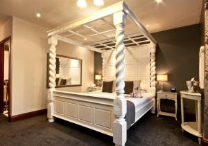 - une chambre avec un lit à baldaquin blanc et un miroir dans l'établissement Broadoaks Boutique Country House, à Windermere