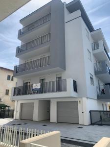 a tall white building with two garage at Matilde Apartments Caorle in Caorle