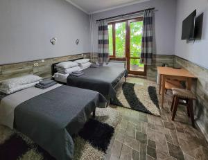 特魯斯卡韋茨的住宿－Glory，客房设有三张床、一张桌子和一台电视。