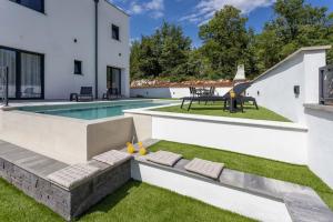 een achtertuin met een zwembad en een huis bij Luxury Sea View Villa DIJANA with Infinity Pool & Jacuzzi Near Rijeka in Kostrena