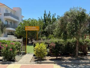 a sign in a garden in front of a building at Cosy apartment at Mythical Sands resort in Paralimni