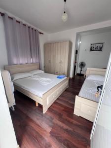 two beds in a bedroom with wooden floors at Vila Endry in Vlorë