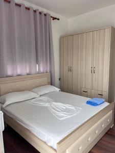a bedroom with a bed with white sheets and wooden cabinets at Vila Endry in Vlorë