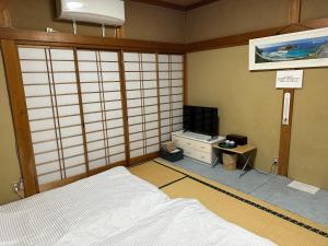 a room with a bed and a tv in it at Guest house En in Fujiyoshida