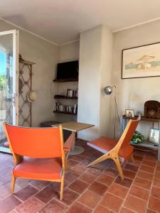 a living room with orange chairs and a table at La maison des Dames Marie in Coursan
