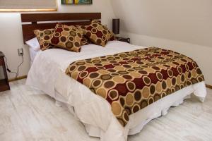 1 dormitorio con 1 cama con edredón marrón y blanco en Hostel Entre Vientos, en Punta Arenas