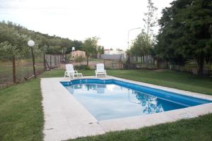 a swimming pool with two chairs in a yard at Koslayna in Potrero de los Funes