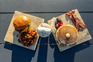 a table topped with two wooden cutting boards with breakfast foods at Under Canvas West Yellowstone in West Yellowstone