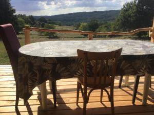 a table and chairs on a deck with a view at La roulotte du bonheur in Saint-Pardoux-la-Rivière