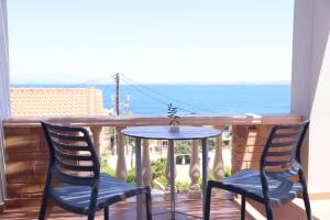 un tavolo e due sedie su un balcone con vista sull'oceano di Chios Shallow Sea a Karfás