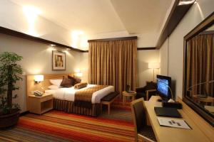 アブダビにあるララビア ホテル アパートメンツのベッドとデスクが備わるホテルルームです。