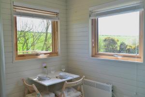 een tafel en twee stoelen in een kamer met twee ramen bij Anniston Mill Cabin 1 in Arbroath