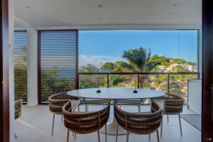 a dining room with a table and chairs and a large window at Casa Capri 601 in Morro de São Paulo