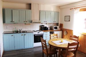 a kitchen with blue cabinets and a table with chairs at Antons Gästhem in Kökar +17 photos