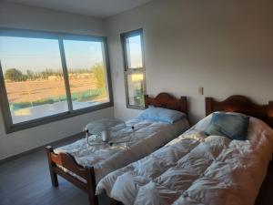 two beds in a room with two windows at Casa En Barrio Privado in Maipú