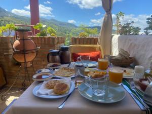 a table with plates of food and glasses of orange juice at Riad Gharnata in Chefchaouen