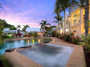 a swimming pool in front of a building at TiTree Village Holiday Apartments in Port Douglas