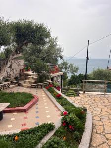 a garden with flowers and benches and the ocean at Vila Endry in Vlorë +19 photos