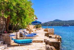 eine Gruppe blauer Stühle und ein Regenschirm neben dem Wasser in der Unterkunft Sea Star in Dubrovnik