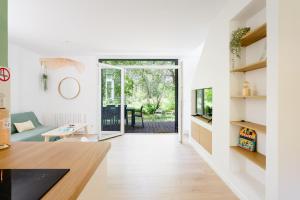 a living room with white walls and a wooden floor at La Cachette du Lac - Parenthèse nature entre piscine, lac & océan in Lacanau