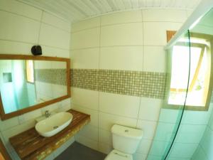 bagno con servizi igienici, lavandino e specchio di Coração da Terra Praia do Rosa a Praia do Rosa