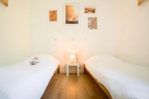two beds in a room with white walls at La Cachette du Lac - Parenthèse nature entre piscine, lac & océan in Lacanau +37 photos