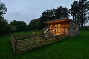 a small wooden cabin in a field with a fence at Anniston Mill Cabin 1 in Arbroath