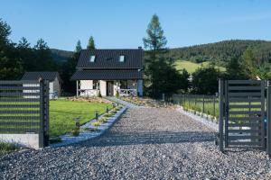 a house with a gate and a gravel driveway at Jastrzębie Gniazdko in Jastrzębik