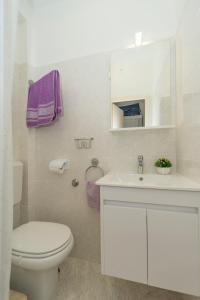a white bathroom with a toilet and a sink at Corcyra Nigra Apartment 2 in Blato +18 photos