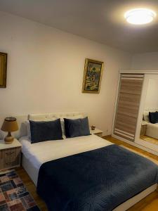 ein Schlafzimmer mit einem großen Bett mit blauen Kissen in der Unterkunft Prishtina Central Apartment in Pristina