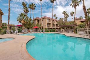una piscina con palmeras y un edificio en Best Western Plus Palm Desert Resort, en Palm Desert