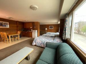 1 dormitorio con cama, sofá y mesa en Raccoon Lodge Motel, en Sylvan Lake