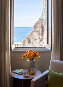 a vase with flowers on a table in front of a window at Anantara Convento di Amalfi Grand Hotel in Amalfi