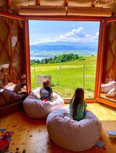 a group of children sitting on bean bags in front of a window at Woda Góry Las - glamping CAŁOROCZNY in Szlembark