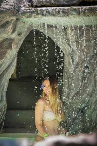 Eine Frau sitzt im Wasser in einem Wasserfall. in der Unterkunft CERRO TUSA SPRINGS in Venecia