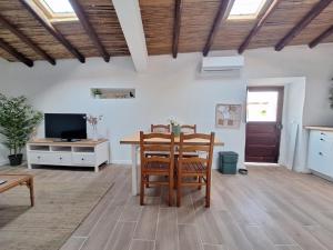 Una sala de estar con una mesa y sillas y un televisor. en Typical house in Algarve 5m from beach, en Porches